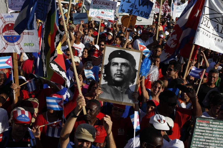 People carry a photograph of revolutionary hero Ernesto Che Guevara during the May Day parade at Havana's Revolution Square May 1, 2012. A red-tinged sea of Cubans marched through Havana's Revolution Square on Tuesday in a May Day parade that affirmed the government's intention of assuring a communist future for the Caribbean island. With President Raul Castro looking on from beneath a giant statue of Cuban independence hero Jose Marti, hundreds of thousands of workers wearing red shirts and waving red flags filed through the vast plaza where Cuba holds its biggest political rallies. REUTERS/Enrique De La Osa (CUBA - Tags: POLITICS BUSINESS EMPLOYMENT) ORG XMIT: EOC09